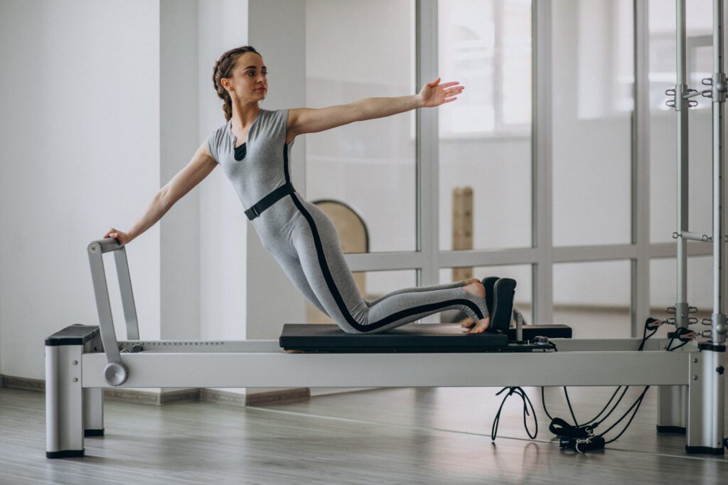 Una mujer haciendo ejercicio en Reformer, una de las máquinas más populares en Pilates.