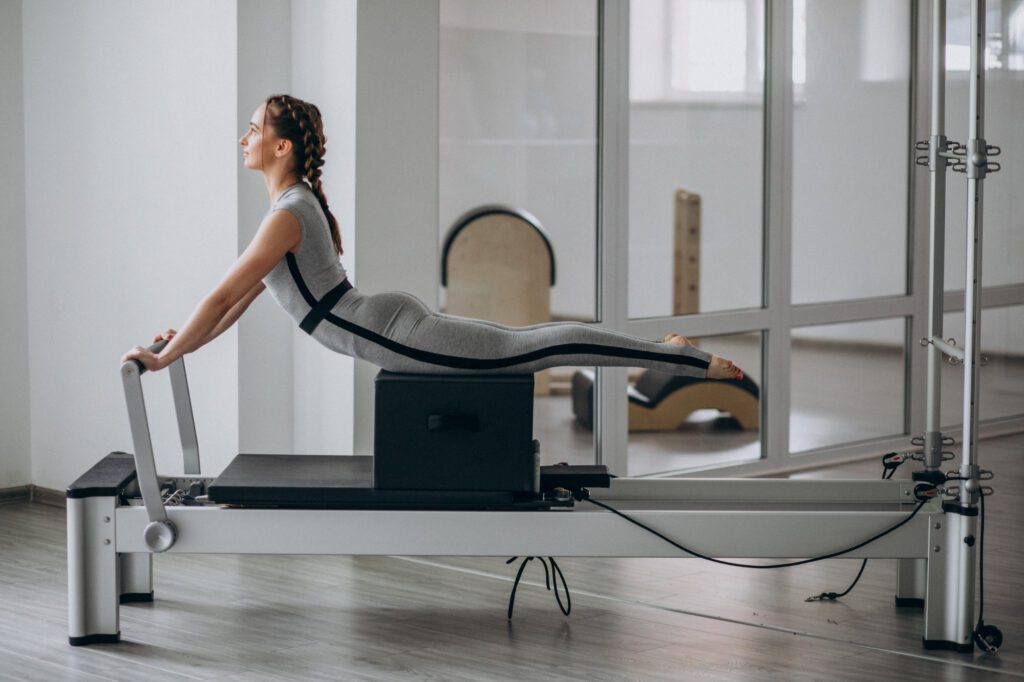 Persona realizando un ejercicio de estiramiento en pilates, mejorando la flexibilidad y la postura.