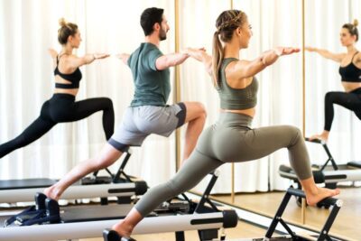 Practicantes de nivel avanzado realizando ejercicios de pilates en máquinas reformer.